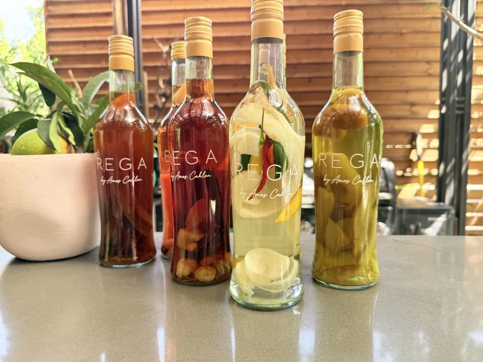 Red and yellow REGA bottles on the bar beside a bowl of leaves and fruit