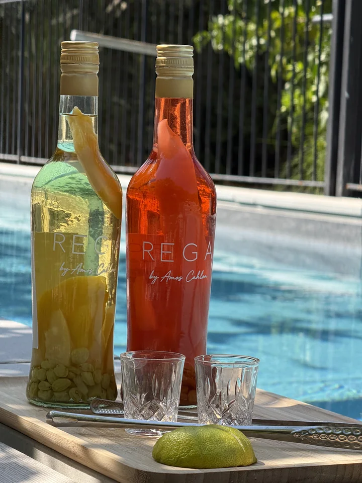 Two REGA bottles with glasses and lime, overlooking blue water