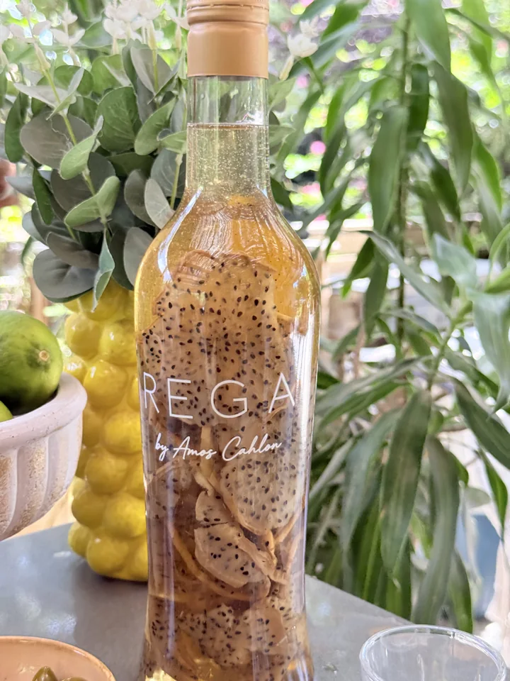 A close-up of a REGA bottle with fruit slices and small seeds