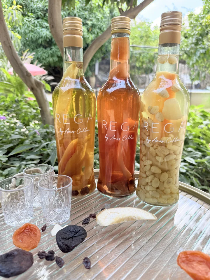 Three golden and orange bottles on a silver tray in the garden